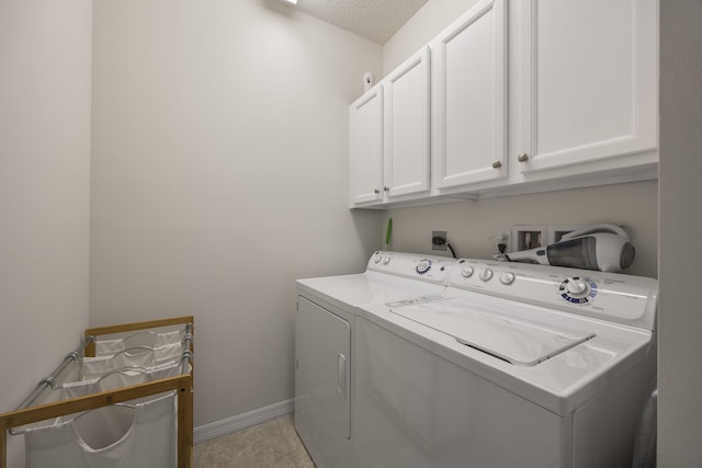 laundry room with a textured ceiling, washing machine and clothes dryer, and cabinets