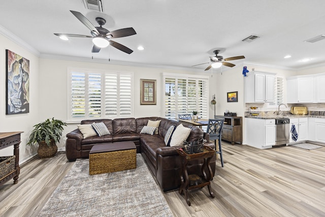 living room with ceiling fan, sink, ornamental molding, and light wood-type flooring