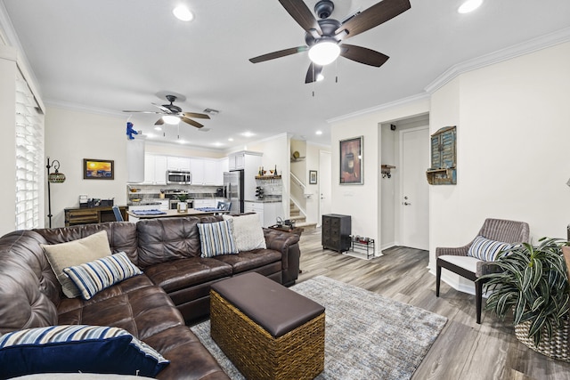 living room with ceiling fan, ornamental molding, and light hardwood / wood-style flooring