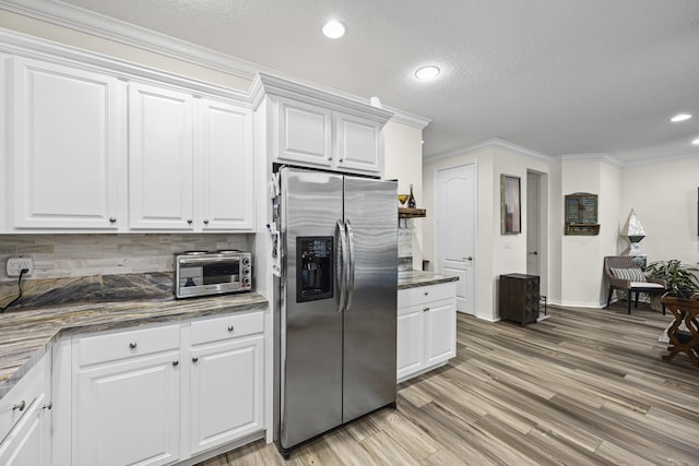 kitchen with stainless steel refrigerator with ice dispenser, white cabinetry, dark stone counters, decorative backsplash, and ornamental molding