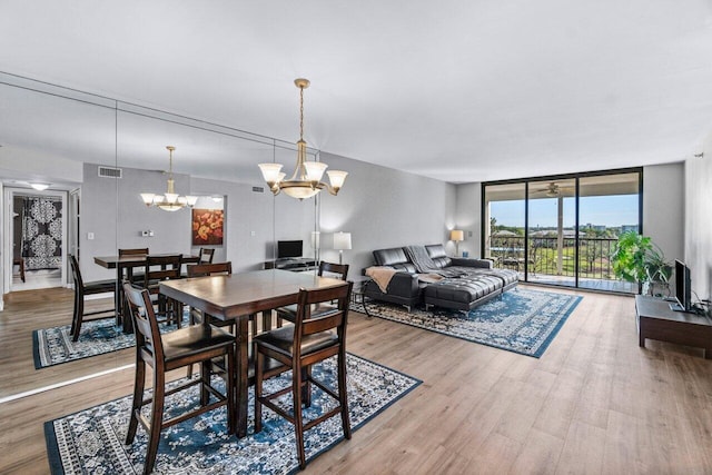 dining area featuring expansive windows, ceiling fan with notable chandelier, and hardwood / wood-style flooring