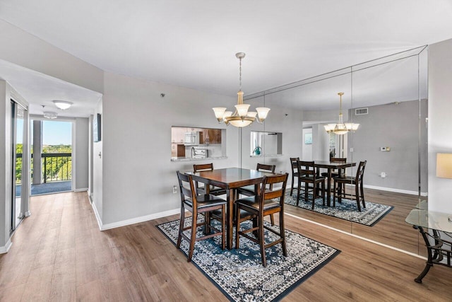 dining area featuring wood-type flooring and an inviting chandelier