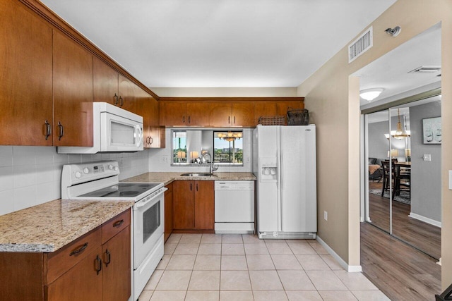 kitchen with light stone countertops, sink, light tile patterned floors, and white appliances