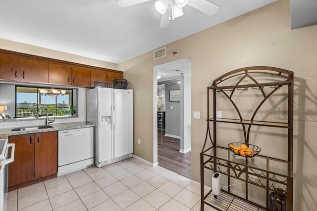 kitchen featuring white appliances, sink, ceiling fan, light stone countertops, and light tile patterned flooring