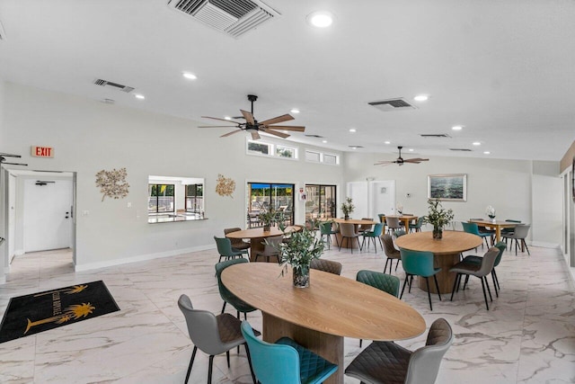 dining space featuring a towering ceiling and ceiling fan