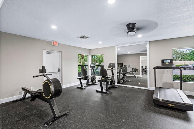 workout area featuring ceiling fan, plenty of natural light, and a textured ceiling