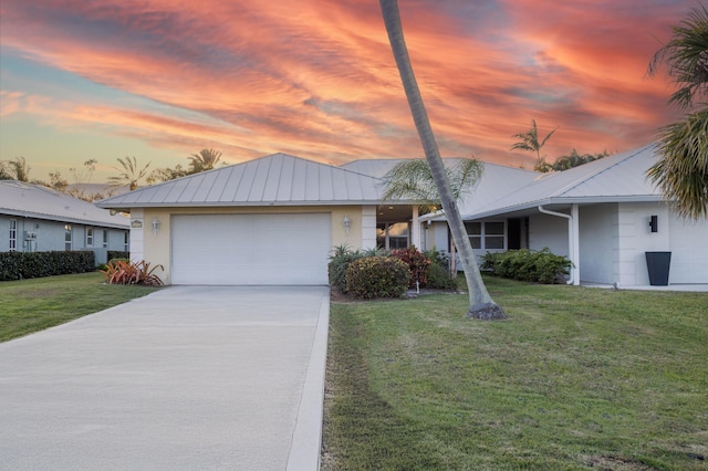 ranch-style home featuring a garage and a lawn