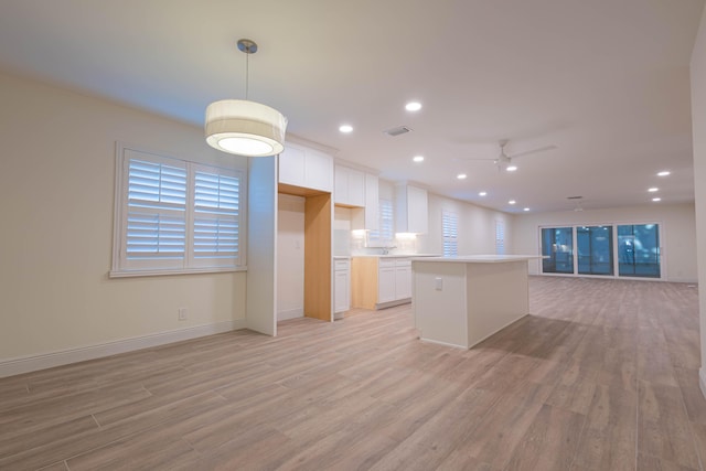 kitchen featuring white cabinets, ceiling fan, decorative light fixtures, and light hardwood / wood-style flooring