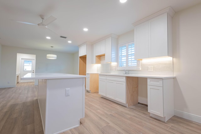 kitchen with decorative backsplash, ceiling fan, decorative light fixtures, white cabinets, and light hardwood / wood-style floors