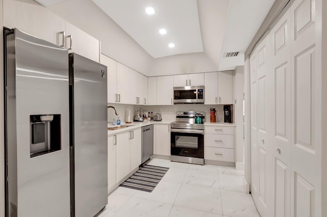 kitchen with lofted ceiling, sink, white cabinets, and appliances with stainless steel finishes