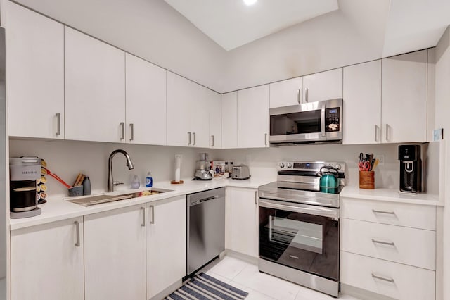 kitchen with white cabinetry, stainless steel appliances, sink, and light tile patterned floors