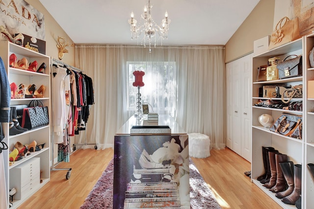 miscellaneous room with lofted ceiling, a notable chandelier, and light wood-type flooring