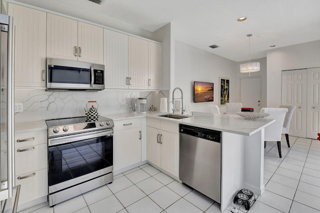 kitchen featuring sink, a notable chandelier, kitchen peninsula, decorative backsplash, and appliances with stainless steel finishes