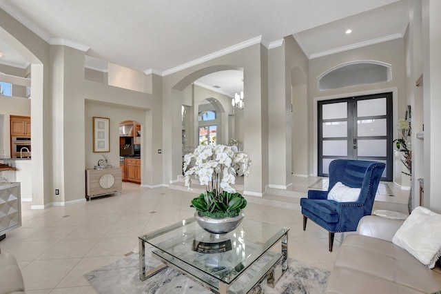 tiled living room featuring french doors, a high ceiling, an inviting chandelier, and ornamental molding