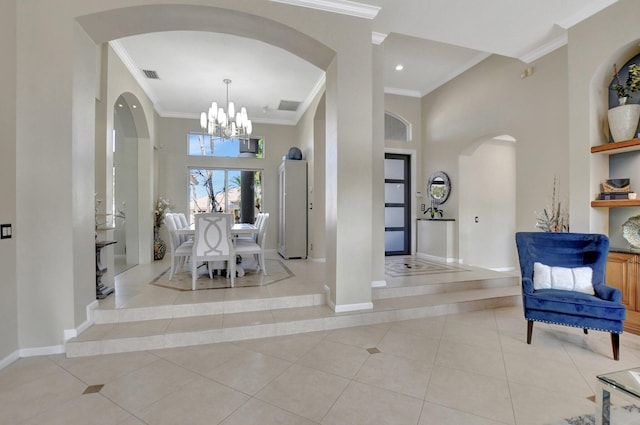 entrance foyer with an inviting chandelier, ornamental molding, and light tile patterned floors