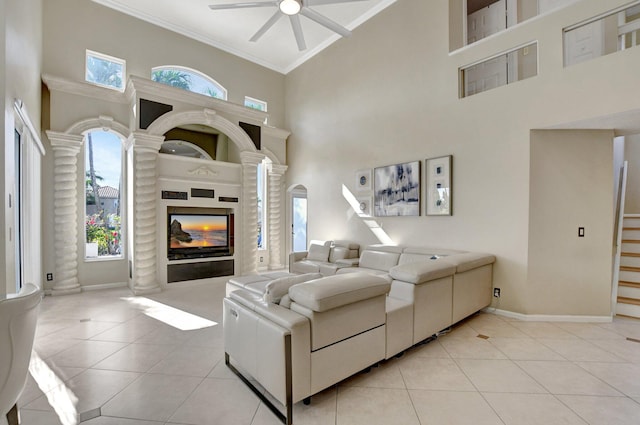 tiled living room featuring a high ceiling, ornamental molding, and ceiling fan