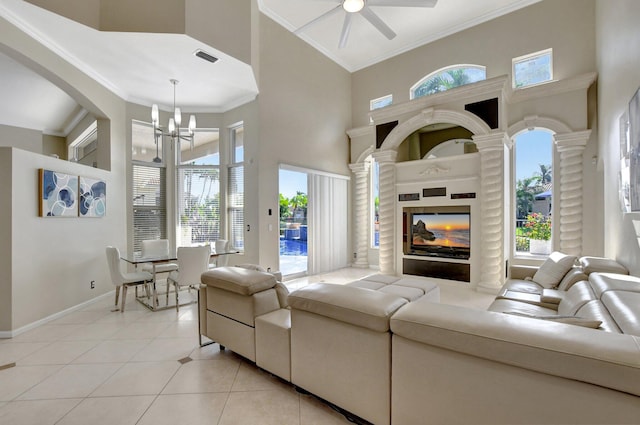 tiled living room with a high ceiling, a healthy amount of sunlight, and ceiling fan with notable chandelier