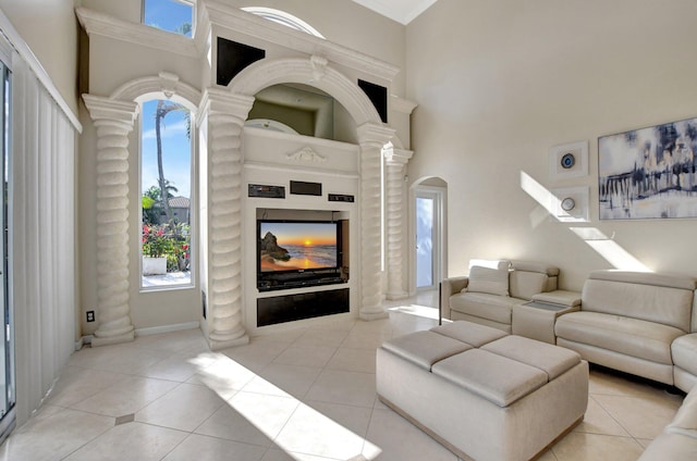 living room with ornate columns, a towering ceiling, and light tile patterned floors