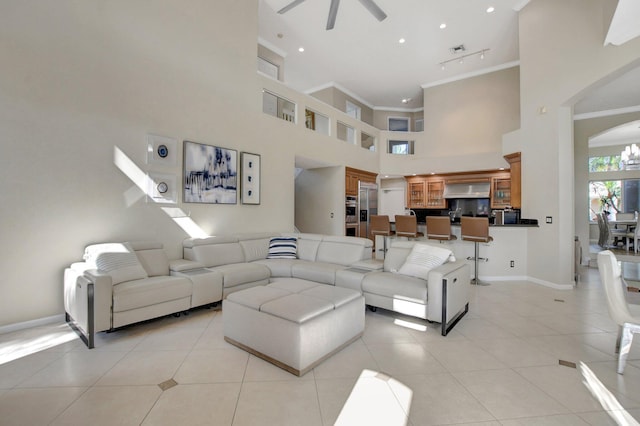 living room featuring a towering ceiling, ceiling fan, light tile patterned flooring, and crown molding