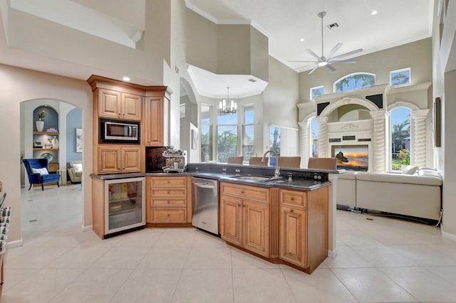 kitchen with decorative light fixtures, a towering ceiling, wine cooler, appliances with stainless steel finishes, and sink