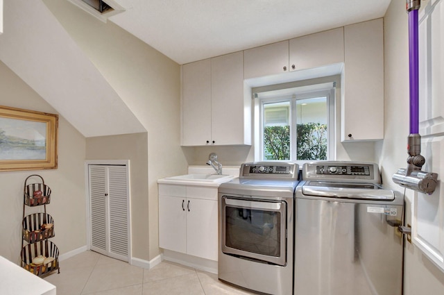 laundry area with cabinets, washing machine and clothes dryer, light tile patterned floors, and sink