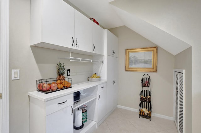 bar featuring lofted ceiling, light tile patterned flooring, and white cabinetry