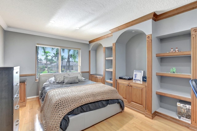 bedroom with a textured ceiling, ornamental molding, and light hardwood / wood-style floors