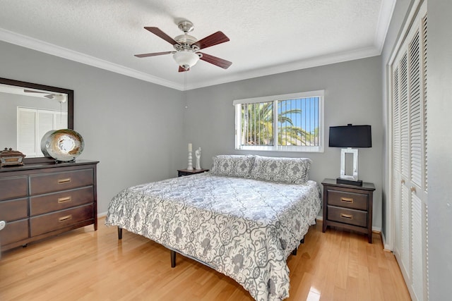 bedroom featuring a textured ceiling, ceiling fan, light hardwood / wood-style flooring, a closet, and crown molding