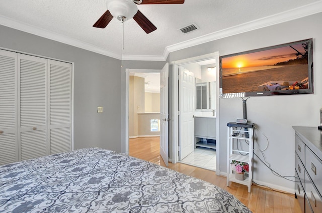 bedroom with a textured ceiling, ceiling fan, a closet, ensuite bath, and crown molding