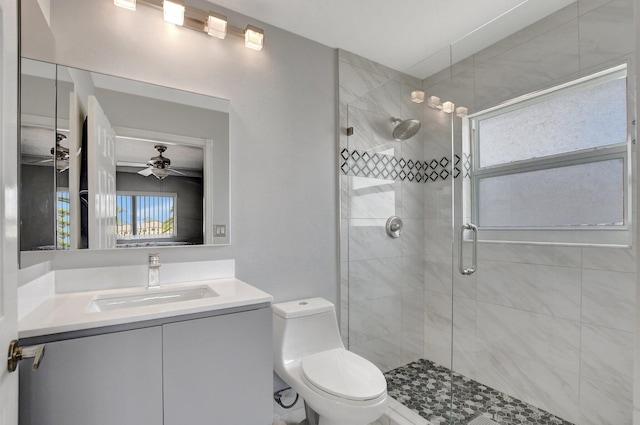 bathroom with ceiling fan, toilet, vanity, and a shower with shower door