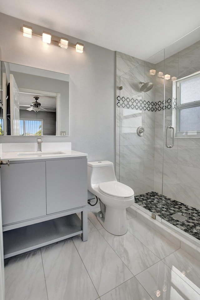 bathroom with ceiling fan, a shower with door, vanity, and toilet