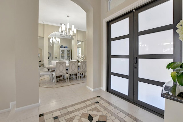 foyer featuring ornamental molding, french doors, an inviting chandelier, and light tile patterned flooring