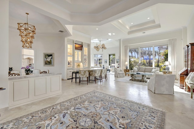 living room featuring a towering ceiling, ornamental molding, a tray ceiling, and a notable chandelier