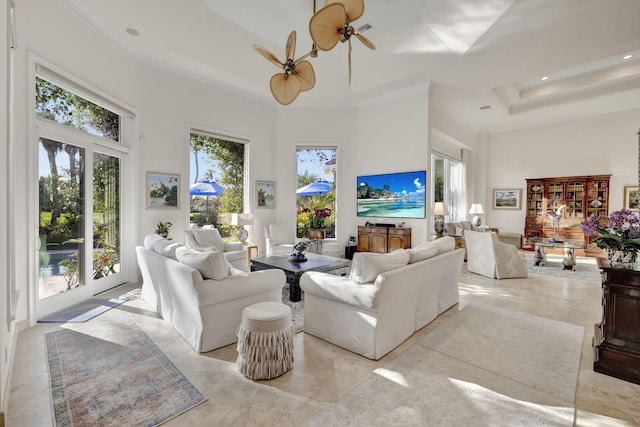 living room with ceiling fan, crown molding, and a high ceiling