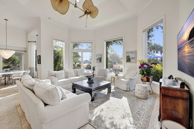 living room with ceiling fan, a tray ceiling, and crown molding