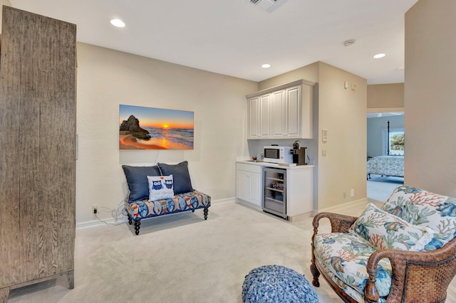 living area with beverage cooler and light carpet