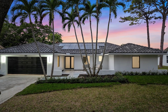 view of front of property featuring a lawn, solar panels, and a garage