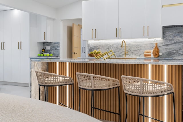 kitchen featuring white cabinets, sink, and tasteful backsplash