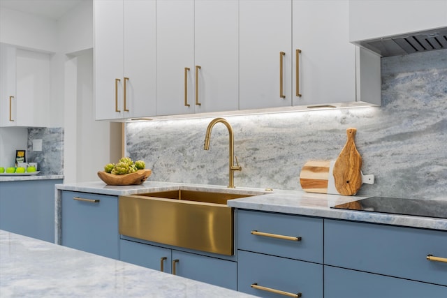 kitchen featuring white cabinets, sink, light stone countertops, and backsplash