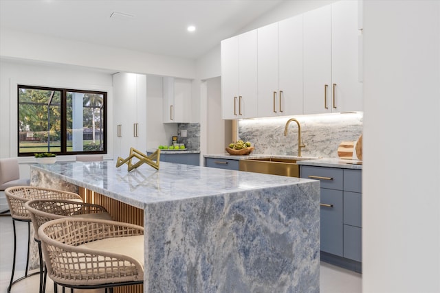 kitchen with white cabinets, a kitchen breakfast bar, a center island, and sink