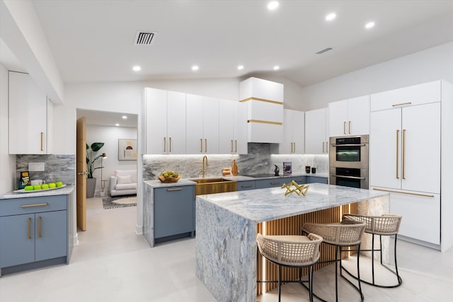 kitchen featuring white cabinetry, a kitchen island, lofted ceiling, and built in fridge