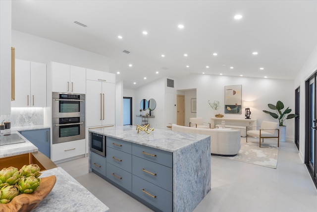 kitchen with built in microwave, white cabinetry, a kitchen island, and lofted ceiling