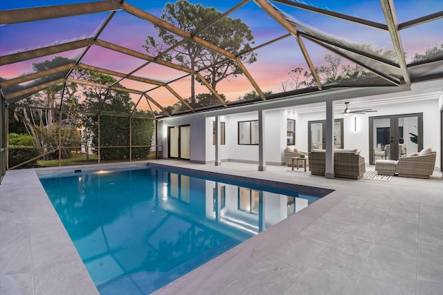 pool at dusk with ceiling fan, a lanai, an outdoor hangout area, and french doors