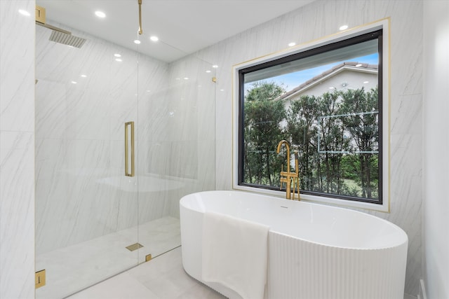 bathroom with tile patterned floors, tile walls, and plus walk in shower