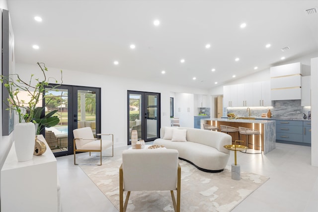 living room with lofted ceiling, sink, and french doors