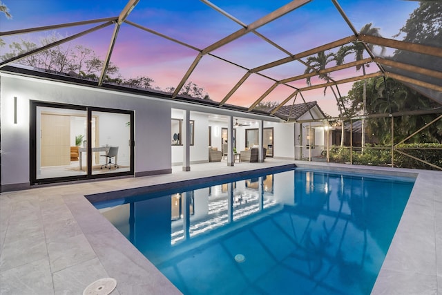 pool at dusk with an outdoor hangout area, glass enclosure, ceiling fan, and a patio area