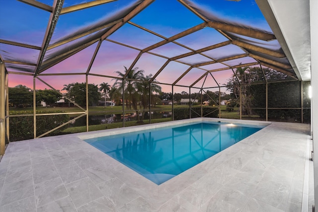 pool at dusk featuring a lanai, a patio, and a water view