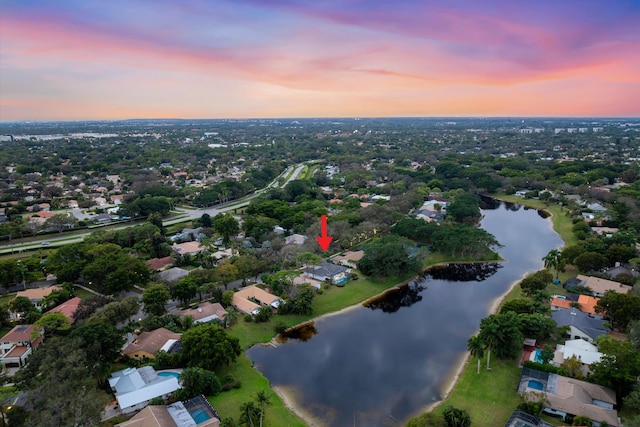 aerial view at dusk featuring a water view