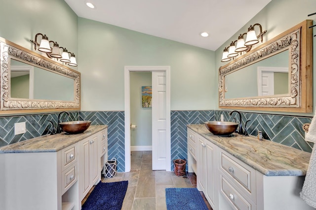 bathroom featuring tile patterned flooring, vanity, lofted ceiling, and tile walls