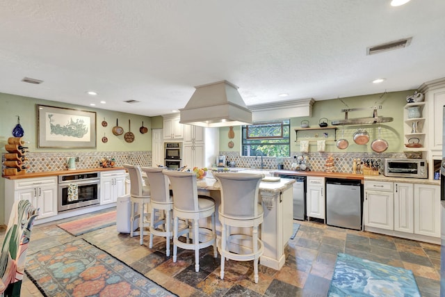 kitchen with a center island, stainless steel appliances, backsplash, a kitchen bar, and white cabinets